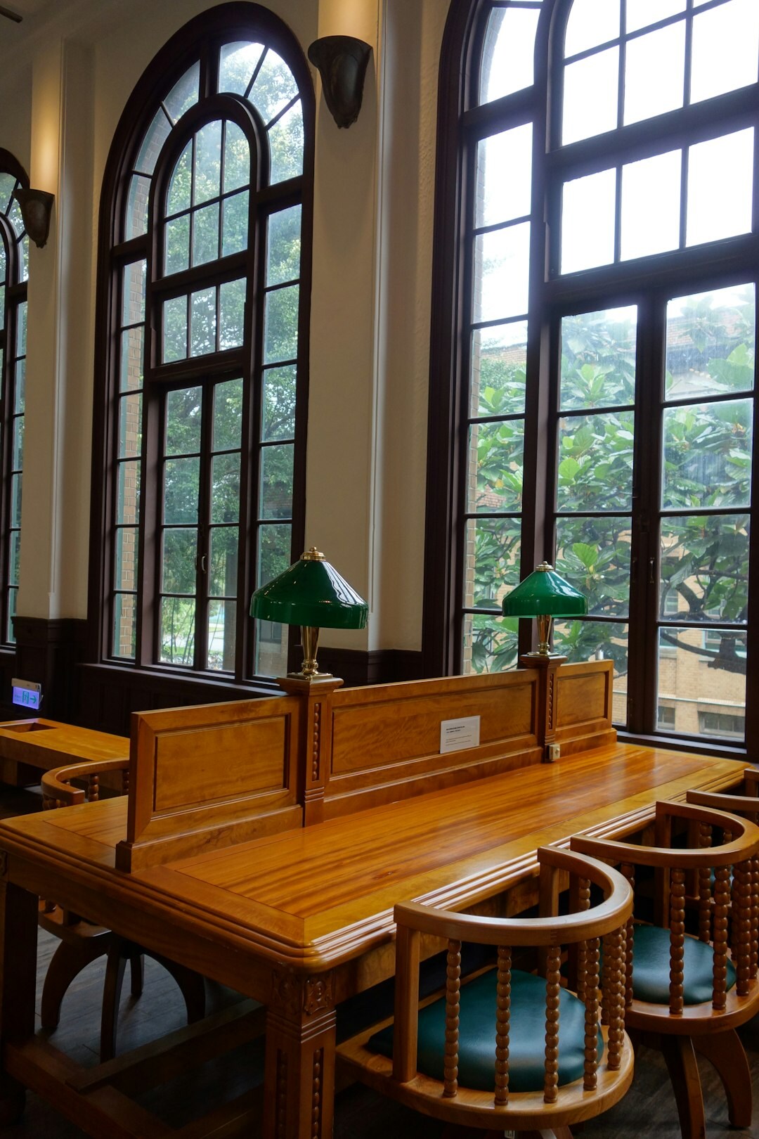Long reading room in an archive with wooden tables and hanging pendant lamps